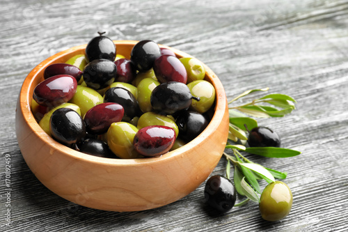 Bowl with different olives on wooden background photo