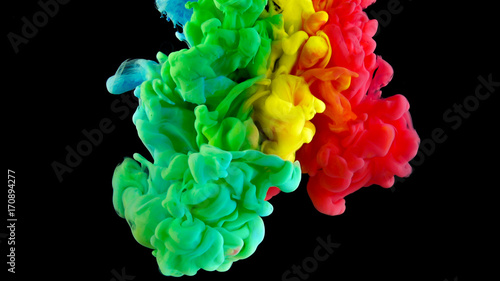 Colorful rainbow paint drops from above mixing in water. Ink swirling underwater. Cloud of ink isolated on black background. Colored abstract smoke explosion effect. Close up view