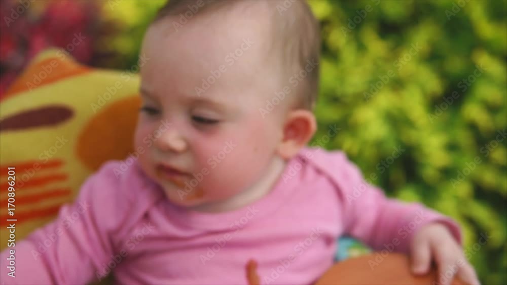 Mom feeding a baby girl with a spoon outdoor. She giving a little daughter healthy vegetable puree Mom feeding a baby girl with a spoon outdoor. She giving a little daughter healthy vegetable puree