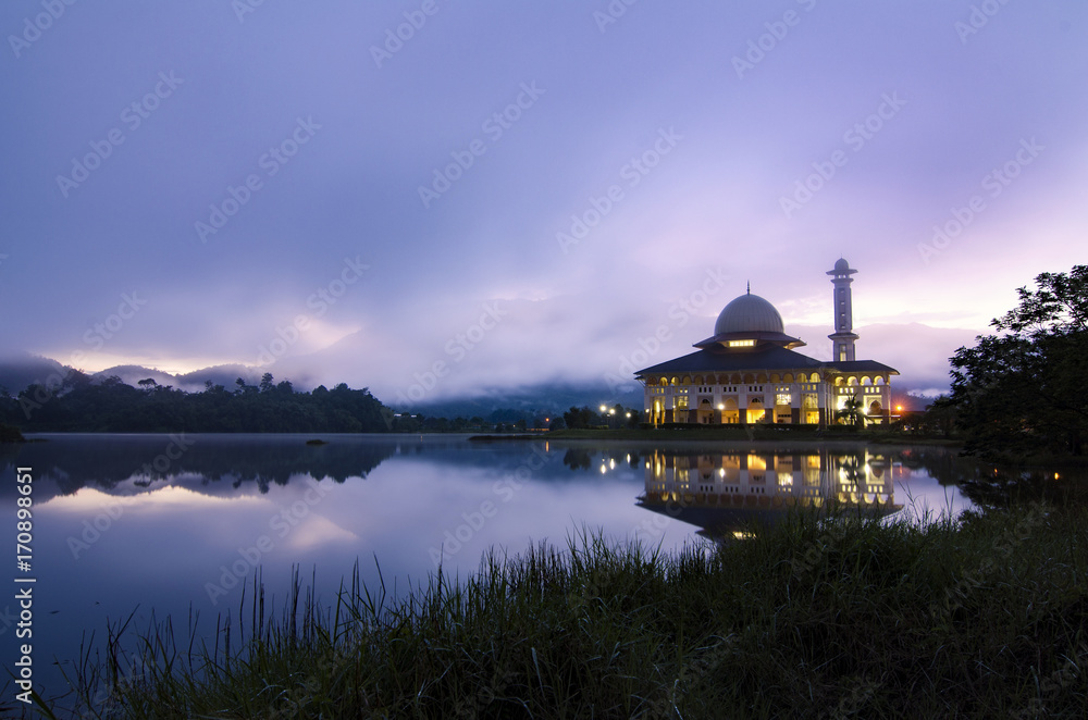 Beautiful morning near the lake, fog cover the hill, reflection and lightiing from the mosque