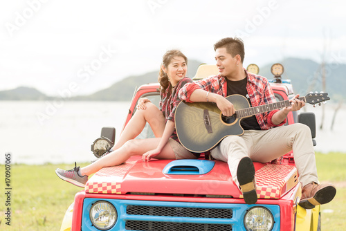 Asian couple having a good time playing guitar during vacation.