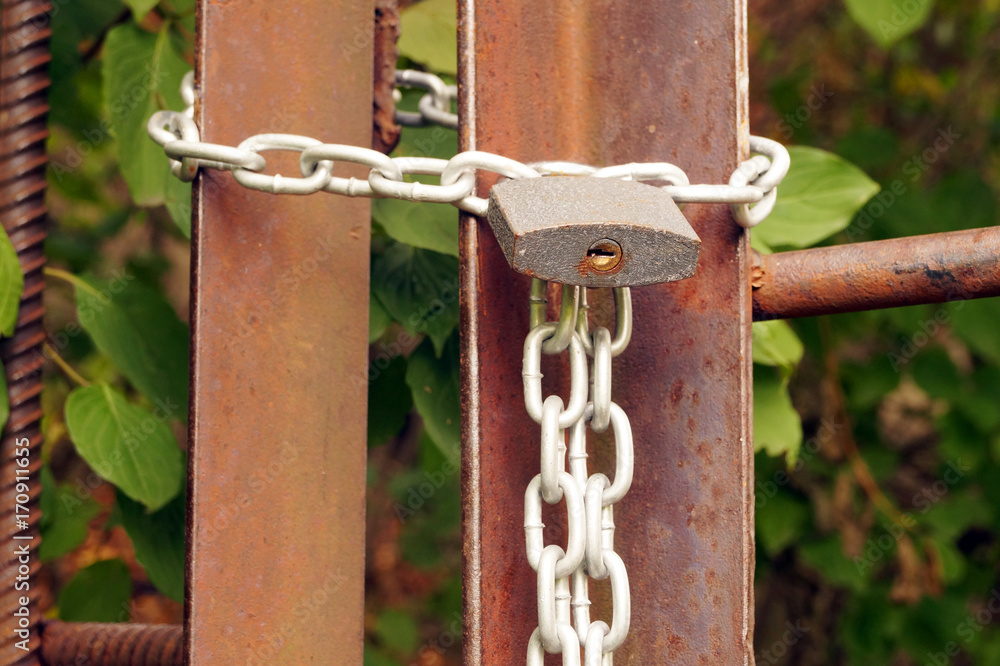 Padlock on the metal chain, locking the entrance. Padlock on the metal chain, locking the entrance.