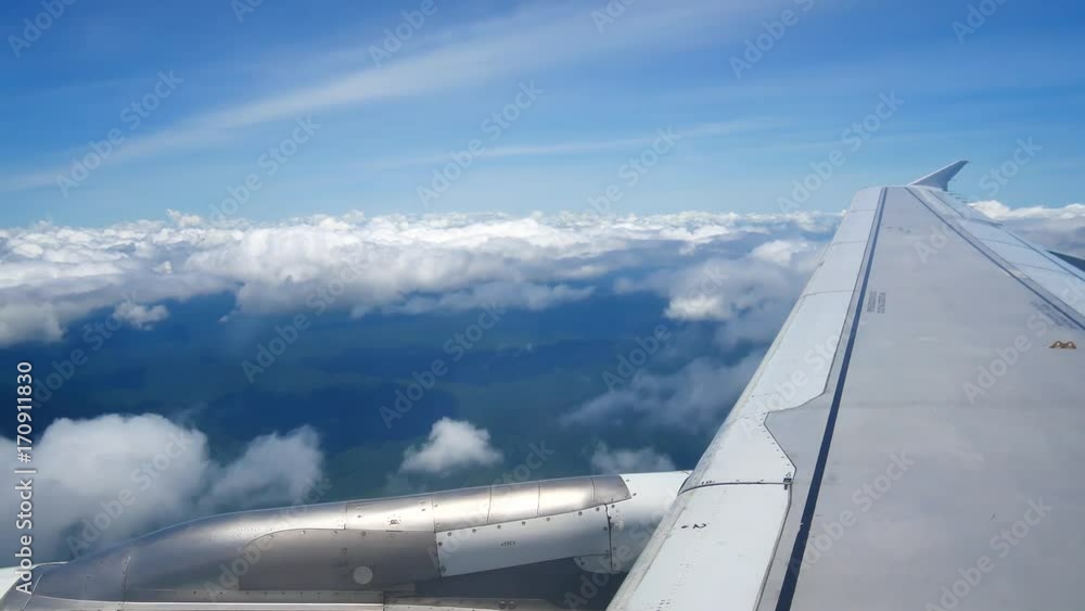 A view from the airplane window over the wings and engines. The planes are flying above the clouds and sky in transportation or travel concept. A view from the airplane window over the wings and engines. The planes are flying above the clouds and sky in transportation or travel concept.
