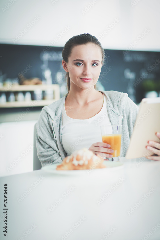 Young woman with orange juice and tablet in kitchen. Young woman with orange juice and tablet in kitchen.