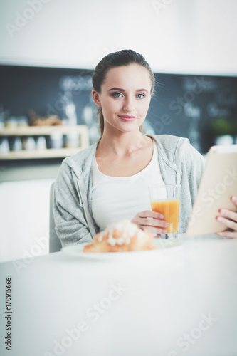 Young woman with orange juice and tablet in kitchen. © lenets_tan