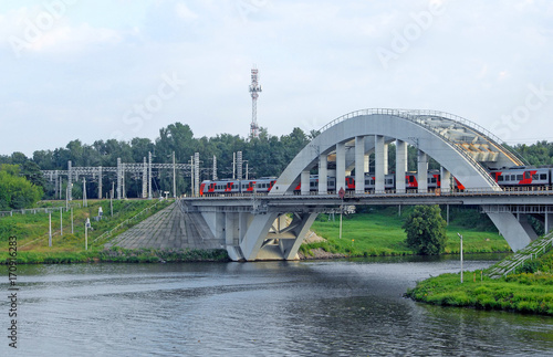 Пригородная скоростная электричка "едет по железнодорожному мосту через канал имени Москвы