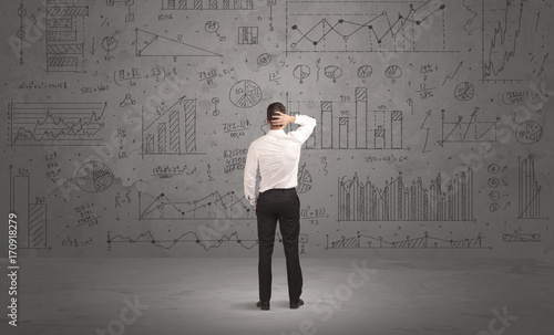 Salesman with business charts on wall