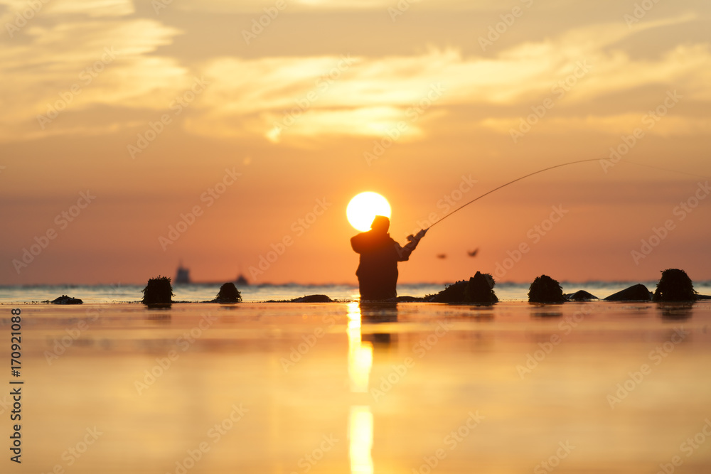 Fototapeta premium Angler bei Sonnenaufgang am Meer