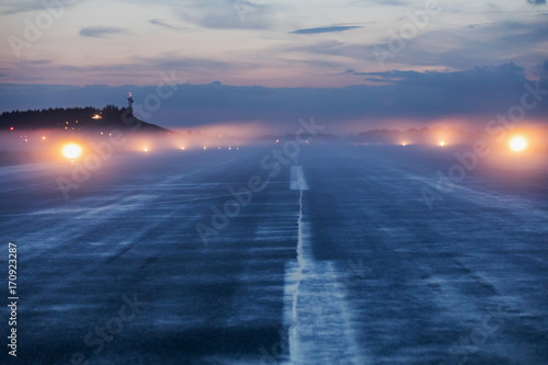 Fotografie Empty runway at airport during a foggy evening