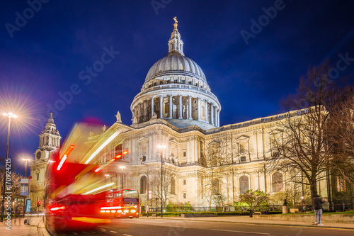 London, England - The Saint Paul's Cathedral with famous old red double decker buses on the move at night