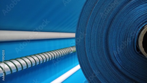 New industrial blue roll, blue background. Concept: material, fabric, manufacture, garment factory, new samples of fabrics.