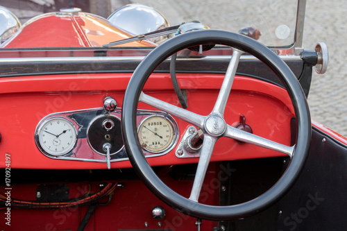 Kutna Hora, Czech Republic - August 18, 2017: Closeup of a red dashboard, with speedometer and steering wheel, of a vintage car parked in the historic city center