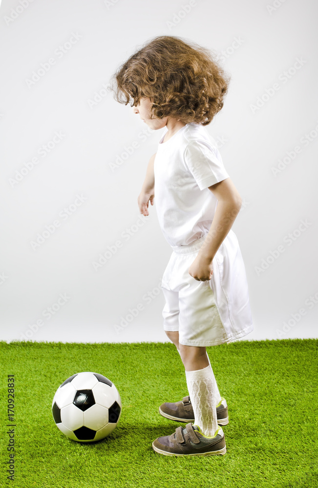 Boy with soccer ball on a gray background.