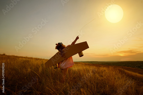 Obraz na plátne Little girl in pilot's suit in field on nature at sunset.
