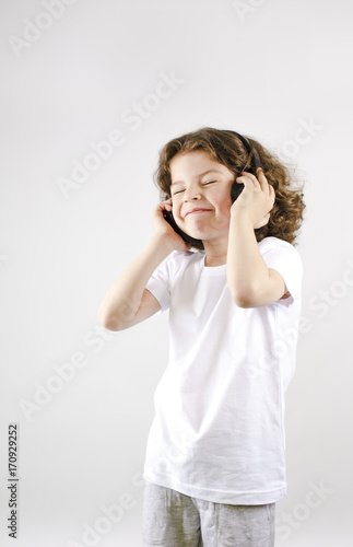 Music and technology concept.Caucasian little boy with headphone on gray background