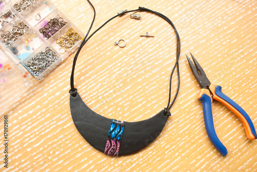 Assembly of bib black necklace. Making jewelry from polymer clay with beads and pliers. Working craft process.