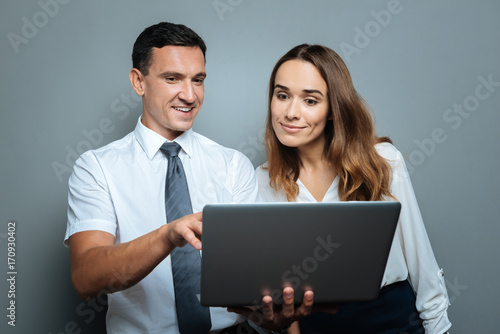 Pleasant cheerful man standing with his colleague