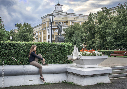 Obraz na płótnie Wight girl sitting on street and dreaming while bird flying away w salonie