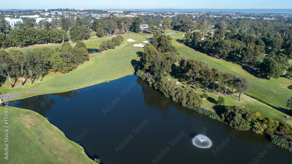 Aerial view of golf course dam with fountain surrounded by fairways, trees and bunkers Aerial view of golf course dam with fountain surrounded by fairways, trees and bunkers