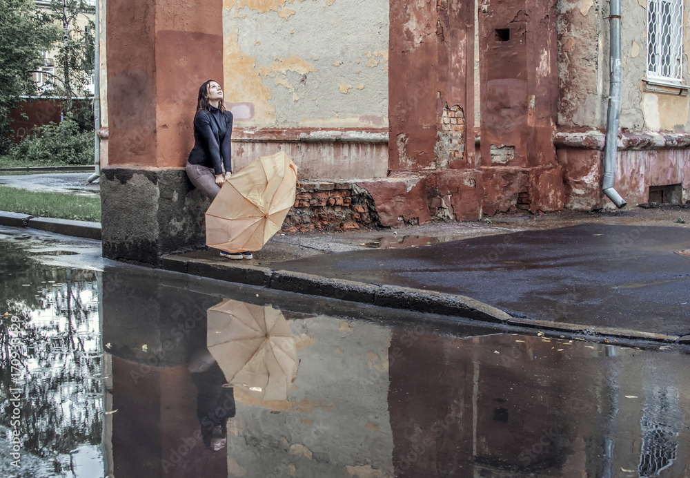 Wight girl sitting alone on street under rain
