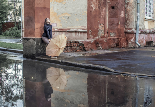 Wight girl sitting alone on street under rain
