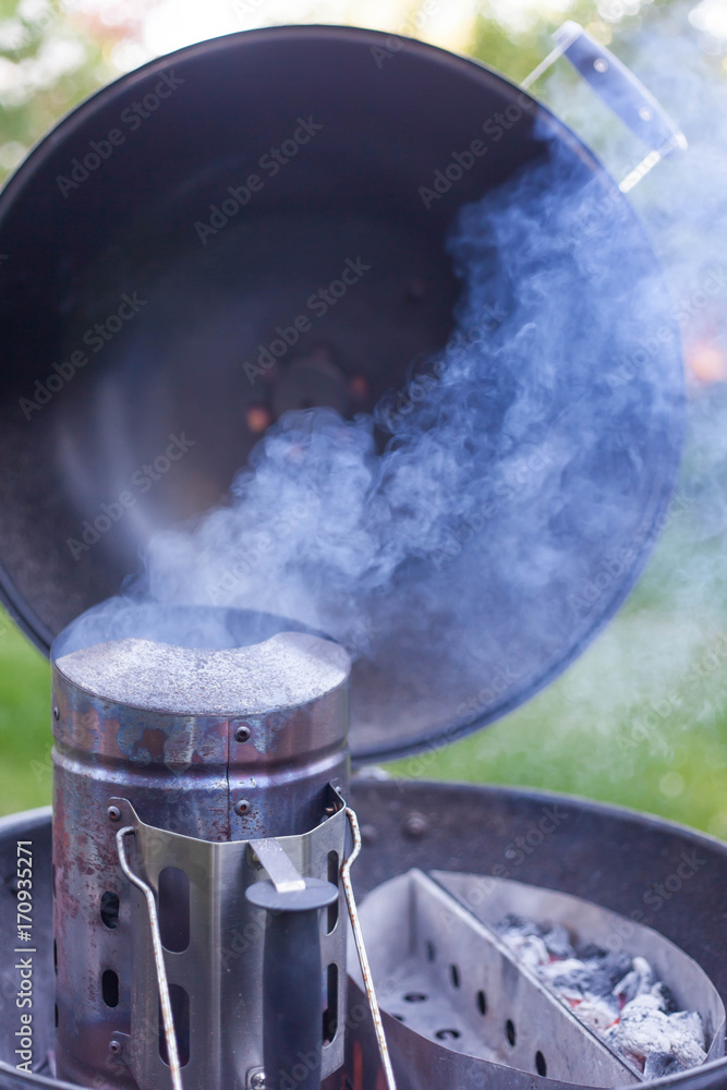 Holzkohle Briketts glühen in Anzündkamin in einem Kugelgrill neben glühender Kohle Holzkohle Briketts glühen in Anzündkamin in einem Kugelgrill neben glühender Kohle