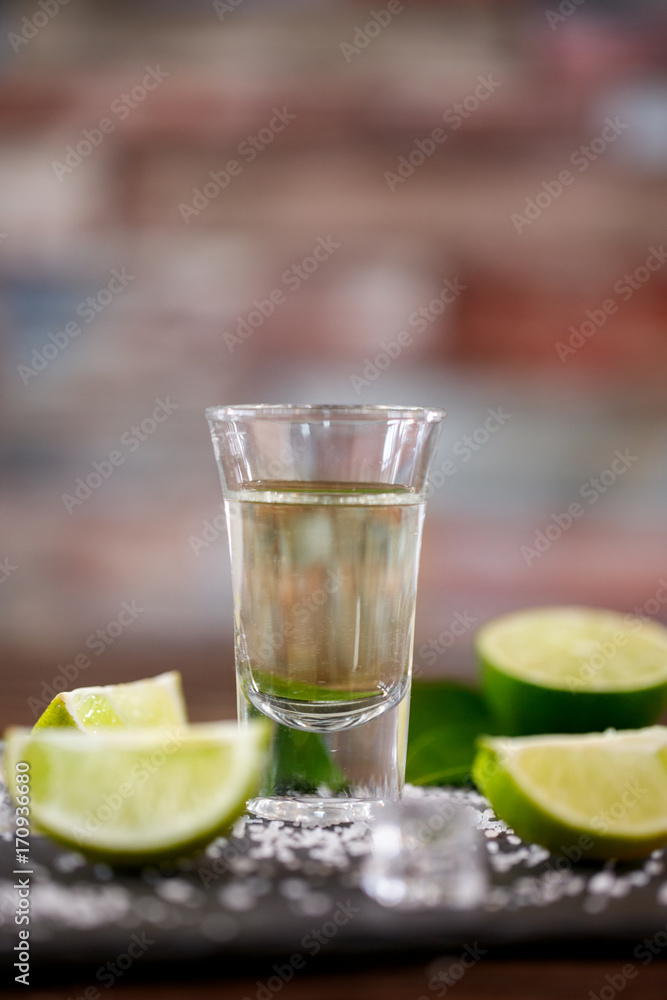Tequila shot with salt, lime and ice background.