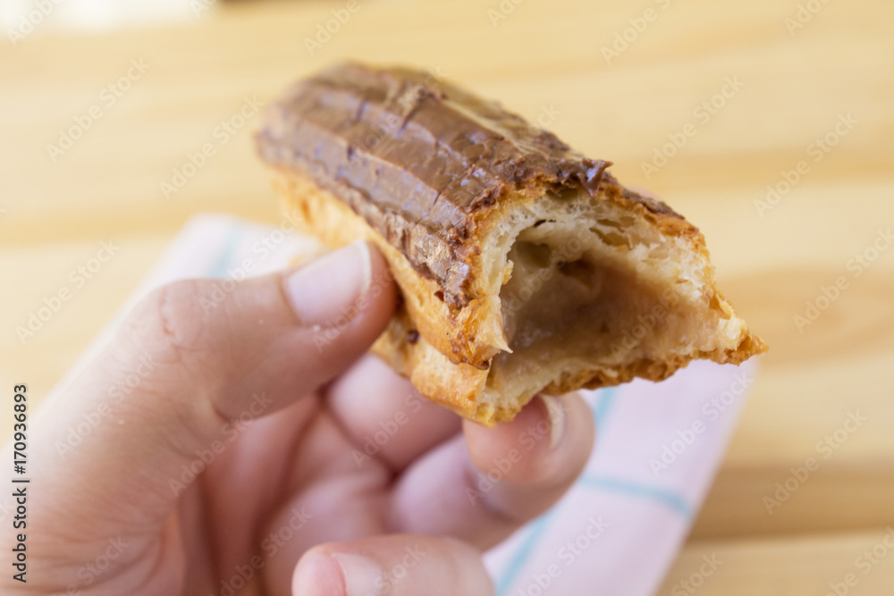 Delicious chocolate eclair on wood table