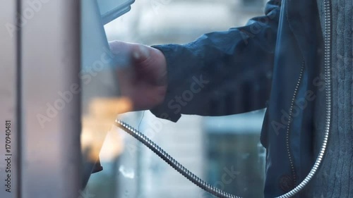 A man with an umbrella in the telephone booth calls and arranges for a meeting