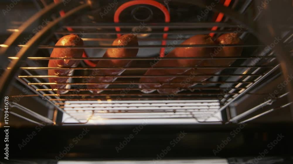 Cooking beef sausages roasted in the oven with broiler. Grilling rack