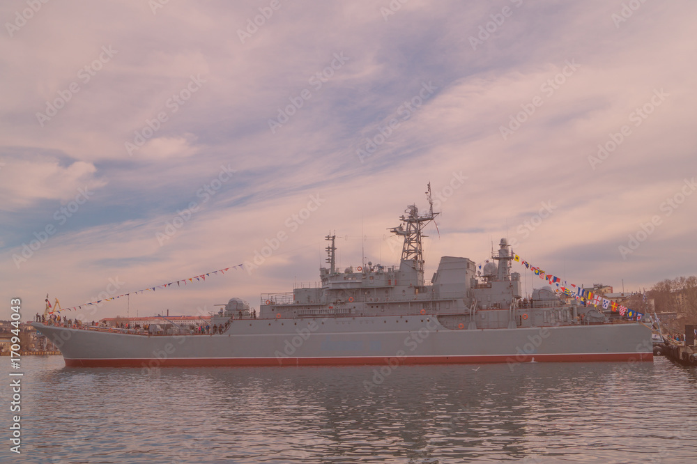 Big military battleship moored to the shore  in the town bay. Toned image