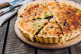 Quiche Lorraine with chicken and vegetables on rustic dark table background. Pie with mushrooms, chicken and broccoli on wooden kitchen board. Traditional French food.