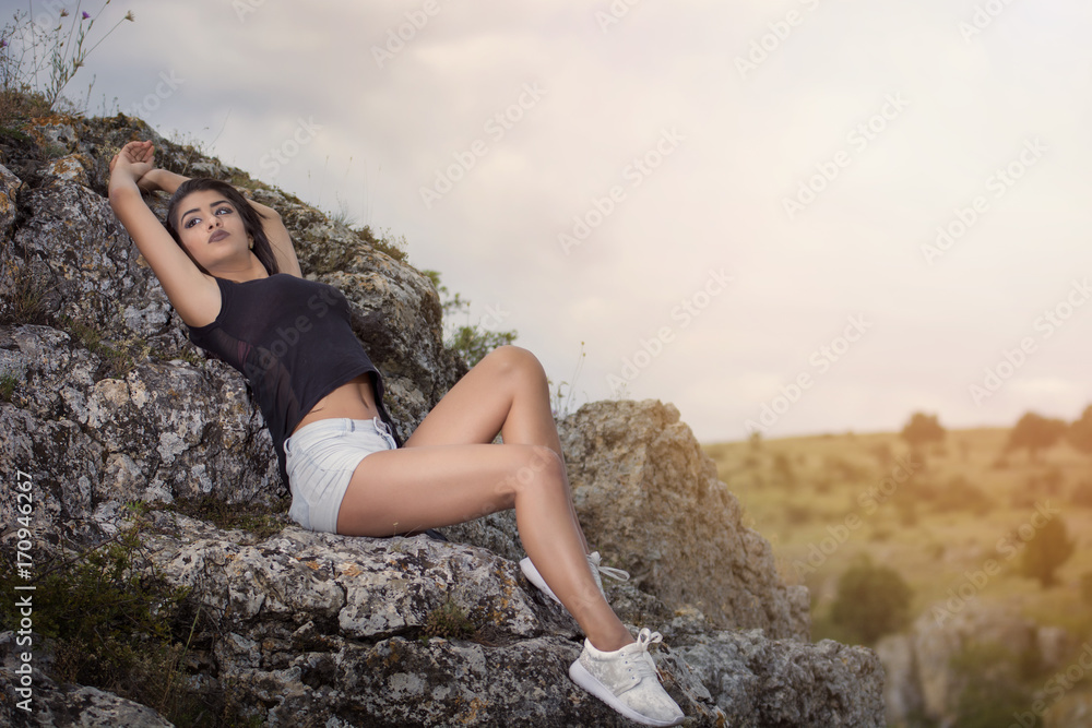 Young girl wearing tshirt and shorts posing on a rock 
