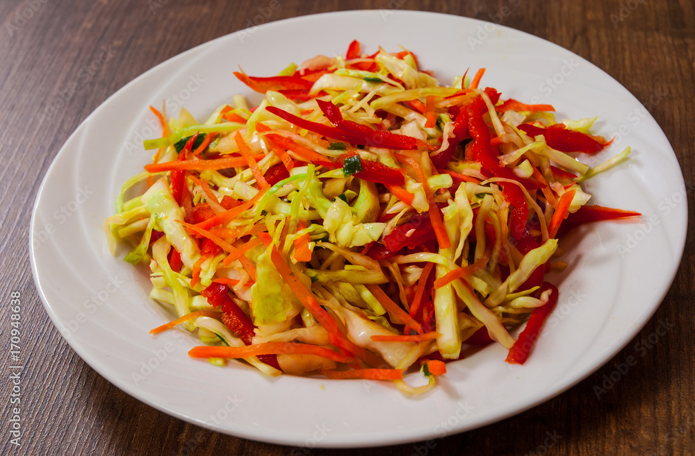 fresh vegetables salad with cabbage and carrot on wooden table.