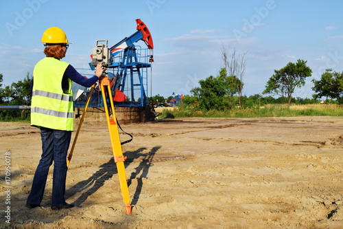 A female engineer - land surveyor at work on an European oil well