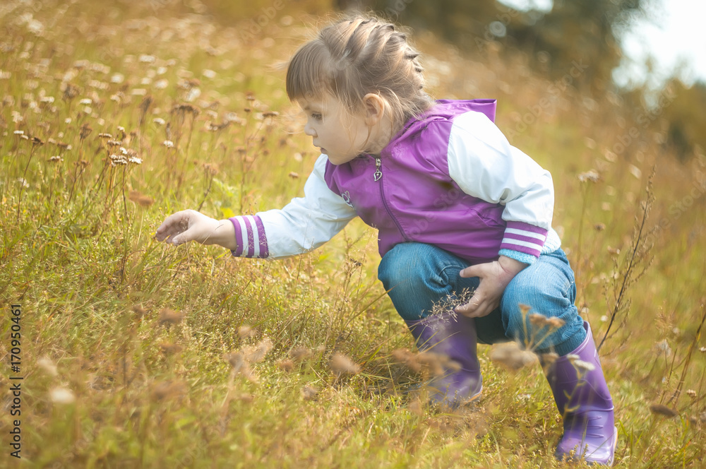 Girl catching a grasshopper in the grass in park Girl catching a grasshopper in the grass in park