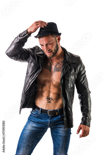 Muscular man with leather jacket on naked torso, wearing fedora hat, isolated on white background in studio