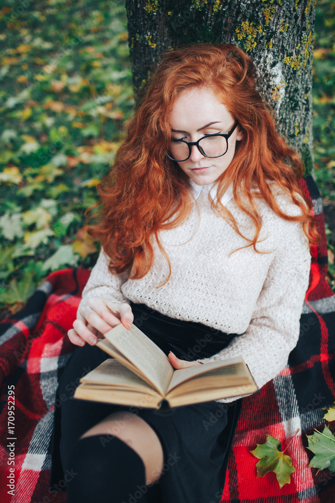 redhead girl reading the book in autumn park redhead girl reading the book in autumn park