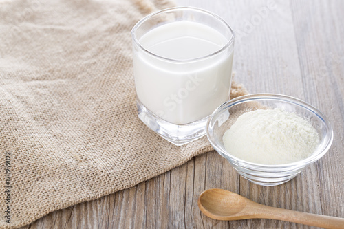 Powdered milk and one glass of milk on the white background.