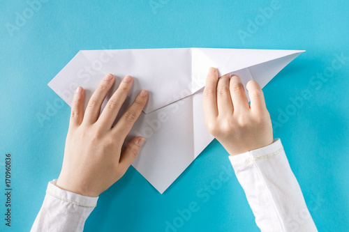 Photography Person's hands folding a paper airplane on a blue background