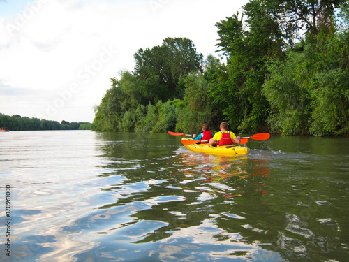 Couple man and girl in a yellow kayak kayaking in wilderness of Danube biosphere reserve