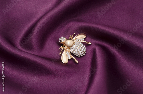 Golden brooch bee with diamonds on silk fabric