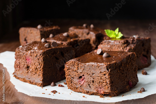 Dark chocolate brownies decorated with mint leaf on wooden table. Closeup view horizontal composition