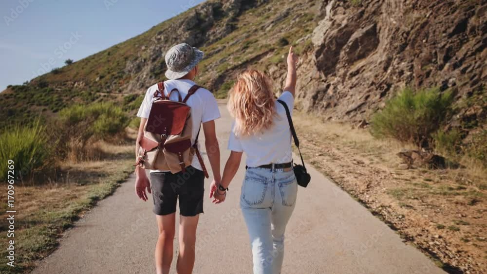 Pretty beautiful people, in trendy outfits, hipster backpack and camera, they hold hands and look around natural surroundings, urban nomads living inspiring adventures Pretty beautiful people, in trendy outfits, hipster backpack and camera, they hold hands and look around natural surroundings, urban nomads living inspiring adventures