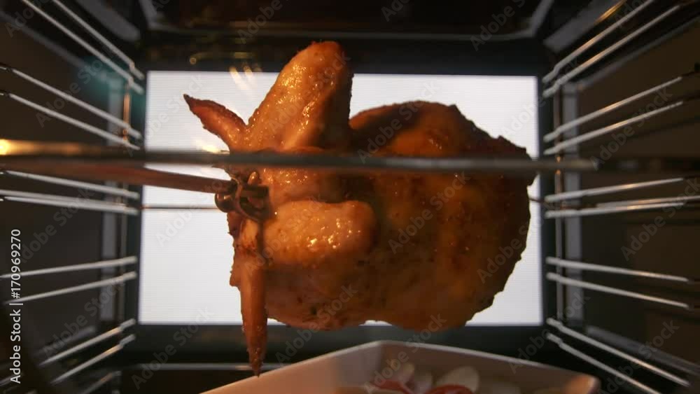 Cooking roasted whole chicken on the rotisserie spit in hot convection