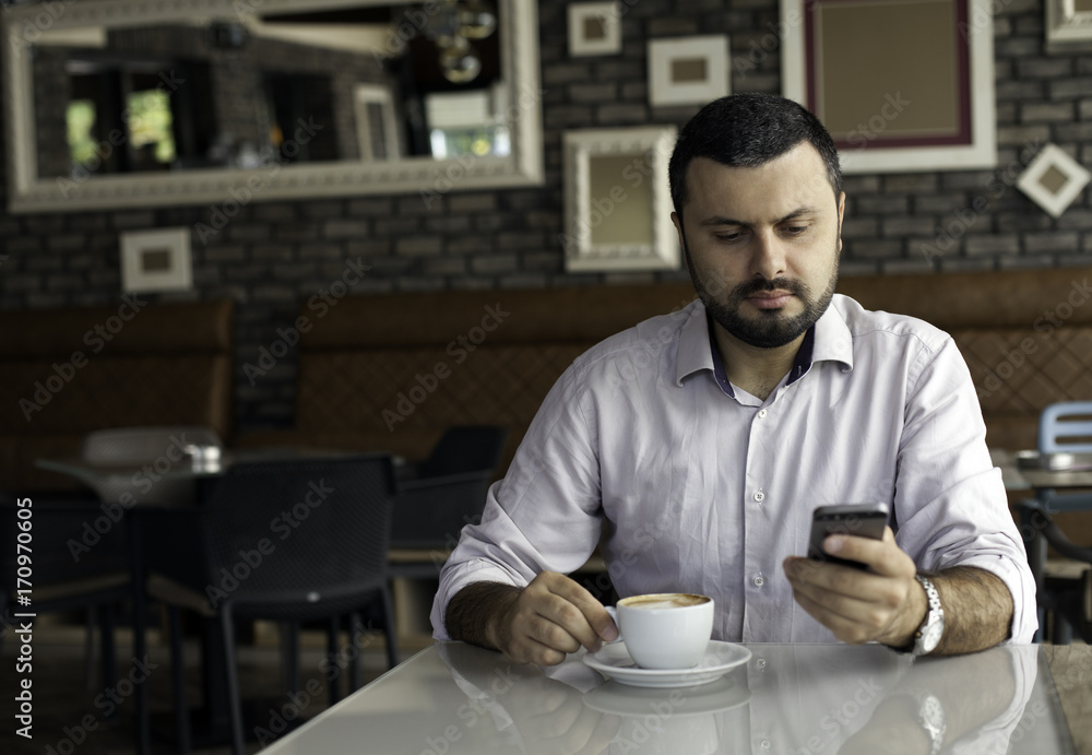Handsome man texting on the phone in cafe Handsome man texting on the phone in cafe