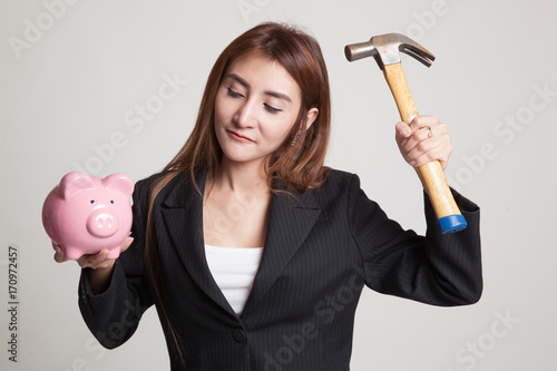 Asian woman with pig coin bank and hammer.