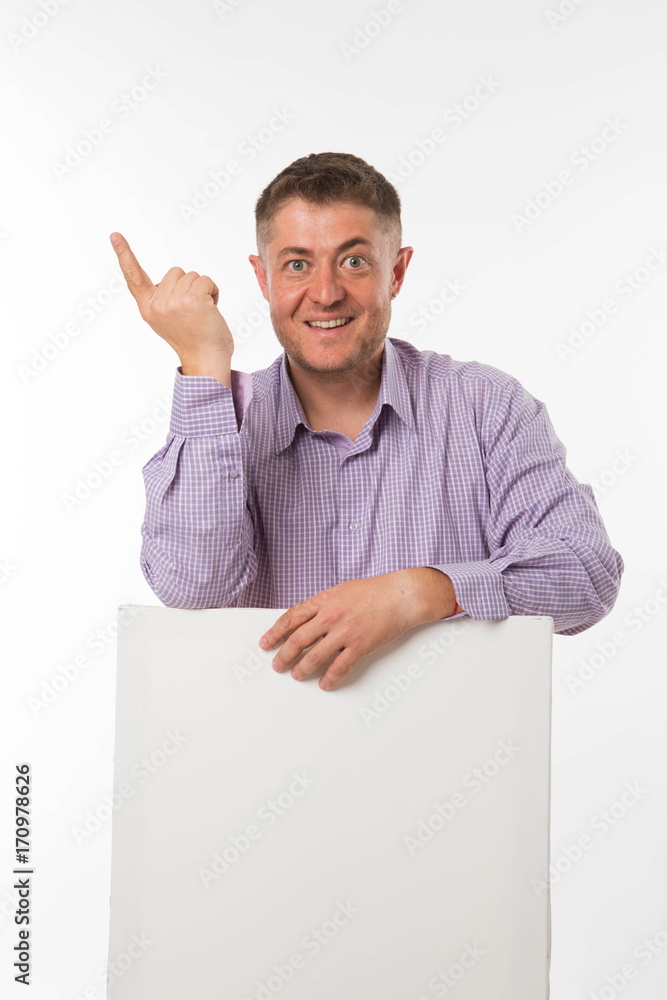 Young enlivened man portrait of a confident businessman showing presentation, pointing paper placard gray background. Ideal for banners, registration forms, presentation, landings, presenting concept.