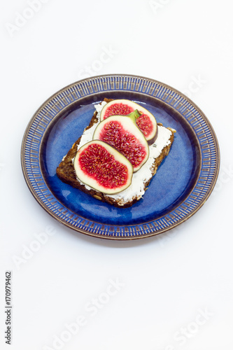 Figs and cheese on a bread. Sandwich on a plate, white background.