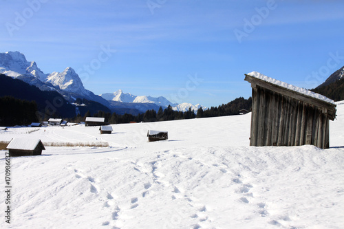 Menschenleere Winterlandschaft im Allgäu mit vielen Hütten und Spuren im Schnee photo